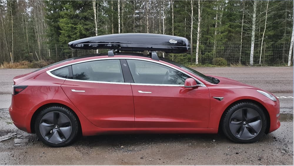 Foto van een Tesla met een dakkoffer die de verkeerde kant op wijst