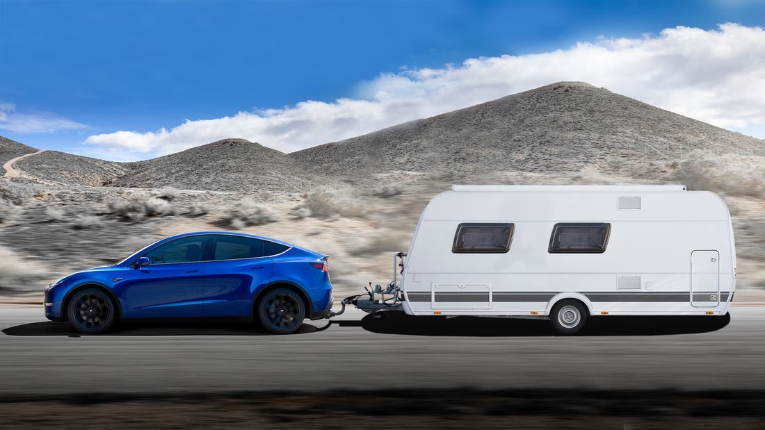 Foto van een blauwe Tesla model Y die een caravan trekt